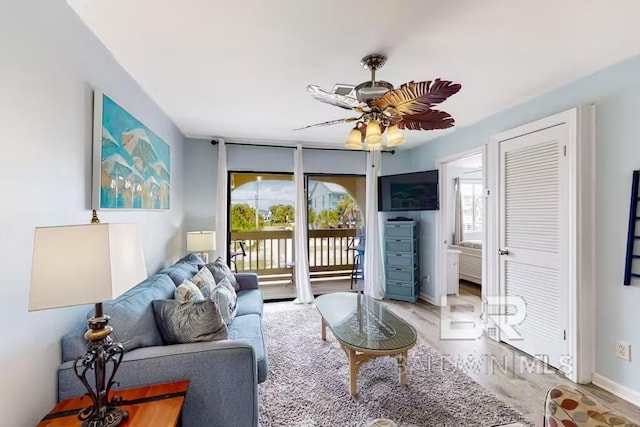 living area featuring ceiling fan, expansive windows, wood finished floors, and a wealth of natural light