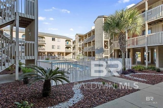 view of property with fence, stairway, and a community pool