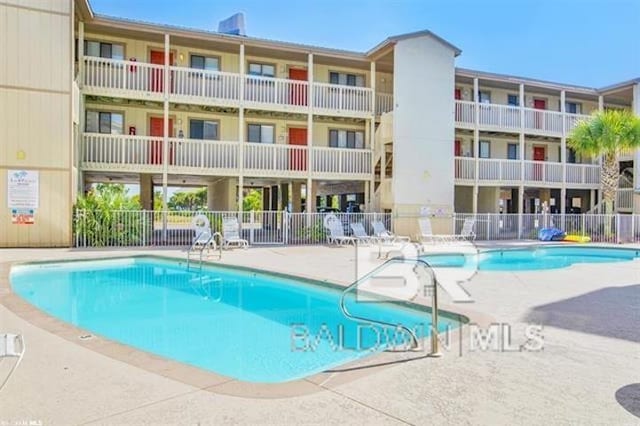 pool with a patio area and fence