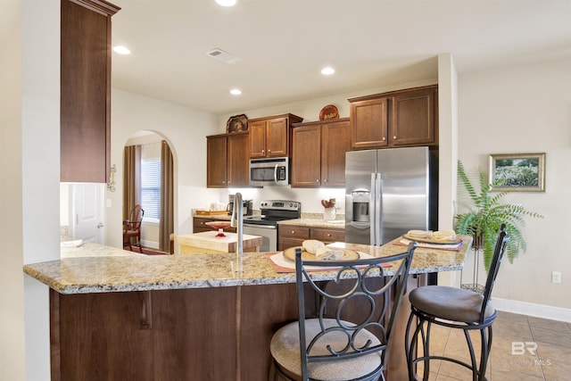 7091 Rocky Road Loop, Gulf Shores, AL 36542 - kitchen with a peninsula, visible vents, arched walkways, light stone countertops, and appliances with stainless steel finishes