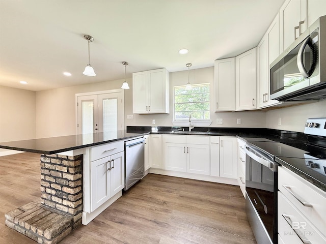 kitchen featuring recessed lighting, a sink, stainless steel appliances, a peninsula, and white cabinets