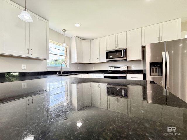 kitchen with a sink, white cabinets, stainless steel appliances, and pendant lighting