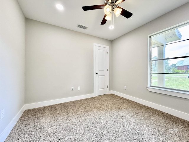 carpeted spare room featuring visible vents, ceiling fan, and baseboards