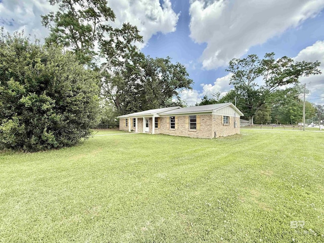 back of property with brick siding, fence, and a yard