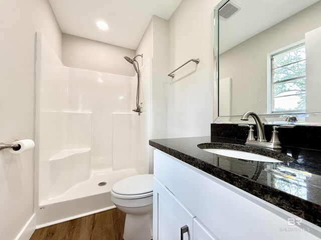full bathroom featuring toilet, a stall shower, wood finished floors, and vanity