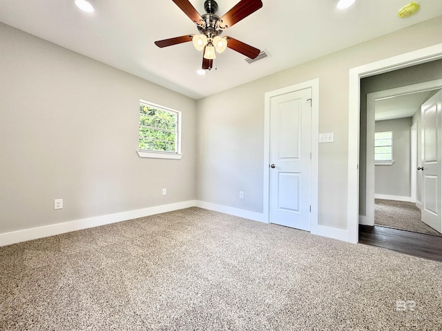 unfurnished bedroom with baseboards, visible vents, dark carpet, and recessed lighting