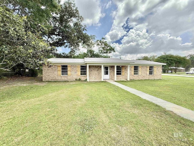ranch-style house featuring metal roof, brick siding, and a front lawn