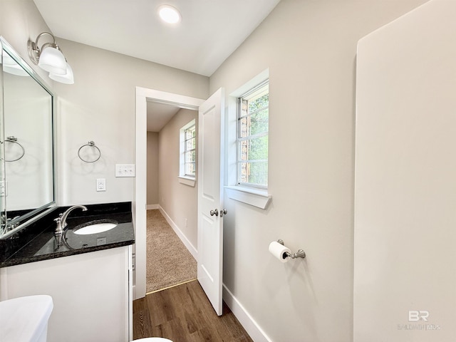 bathroom with toilet, wood finished floors, vanity, and baseboards