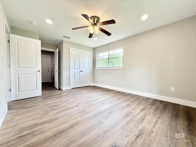 unfurnished bedroom with baseboards, visible vents, wood finished floors, and a closet