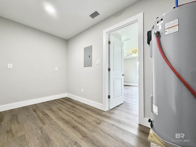 unfurnished room featuring visible vents, wood finished floors, electric panel, and baseboards
