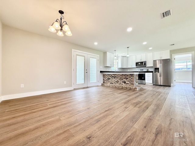 kitchen featuring appliances with stainless steel finishes, visible vents, baseboards, light wood-type flooring, and a notable chandelier