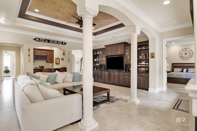 living area with crown molding, light tile patterned flooring, ceiling fan, arched walkways, and a tray ceiling