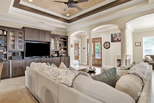 living room with arched walkways, a ceiling fan, decorative columns, a tray ceiling, and visible vents