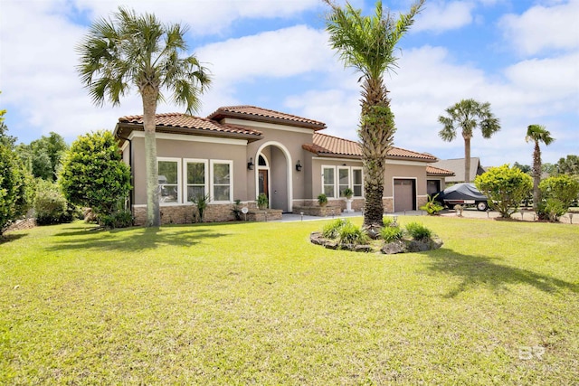 mediterranean / spanish-style home featuring a garage, stucco siding, a front lawn, and a tiled roof