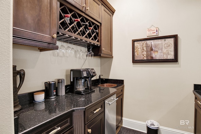 bar featuring a bar, baseboards, stainless steel dishwasher, and a sink