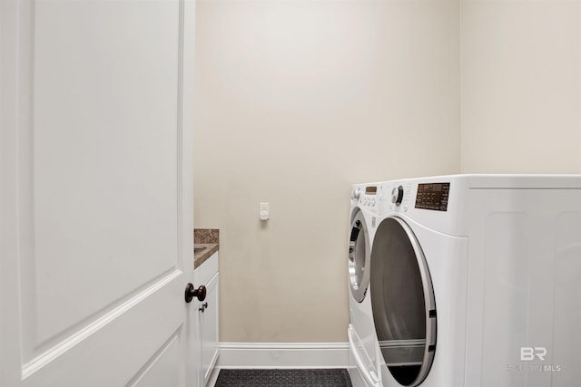 washroom with baseboards, cabinet space, and washing machine and clothes dryer