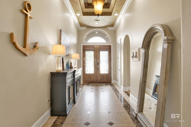 foyer entrance featuring a high ceiling, arched walkways, french doors, baseboards, and ornamental molding