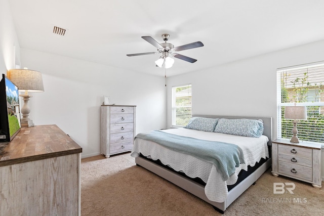 bedroom with multiple windows, ceiling fan, and light colored carpet