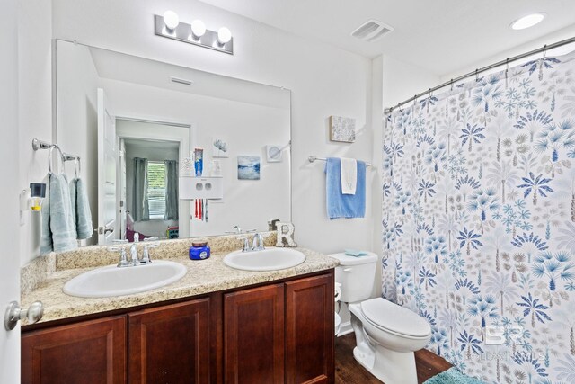 bathroom with toilet, hardwood / wood-style floors, and dual bowl vanity