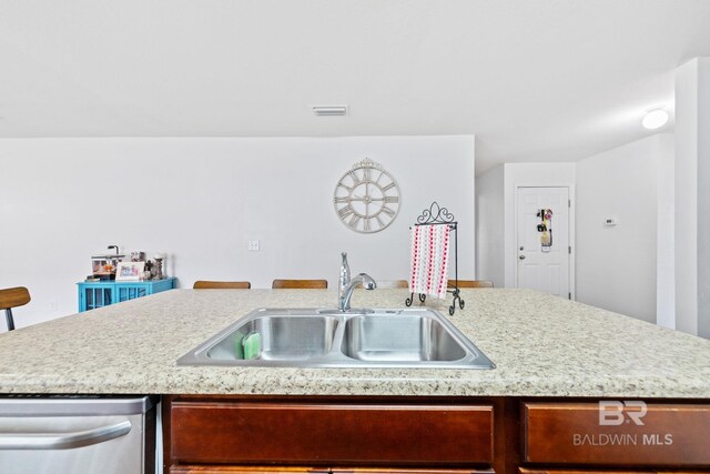 kitchen with dishwasher, sink, a center island with sink, and a kitchen bar