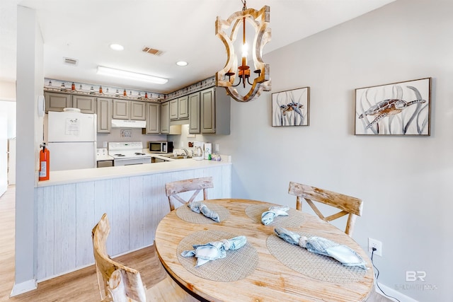 dining area with sink, an inviting chandelier, and light wood-type flooring