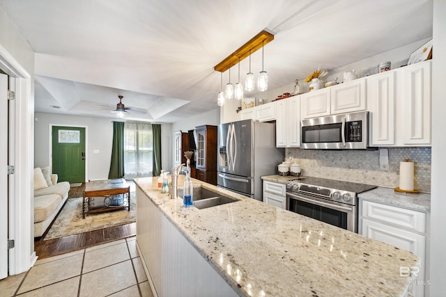 kitchen featuring sink, tasteful backsplash, appliances with stainless steel finishes, a raised ceiling, and pendant lighting