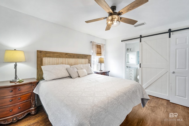 bedroom with ceiling fan, wood-type flooring, a barn door, and ensuite bathroom