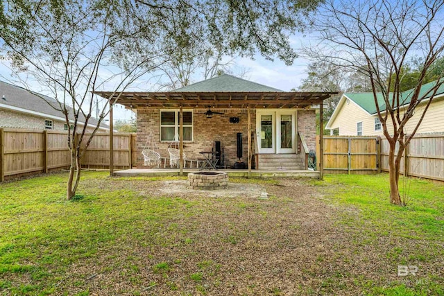 rear view of property featuring a patio, a lawn, and a fire pit