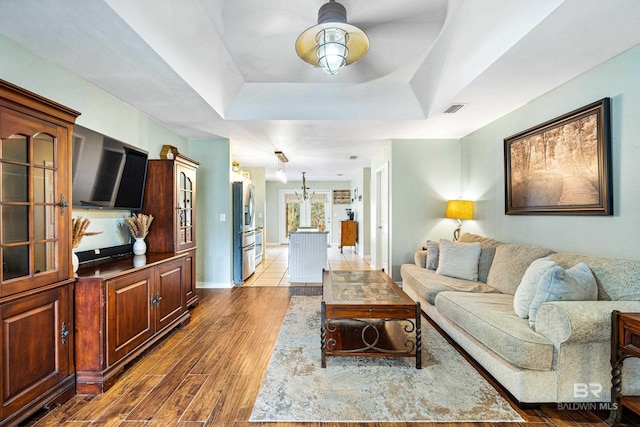 living room with a tray ceiling and dark wood-type flooring