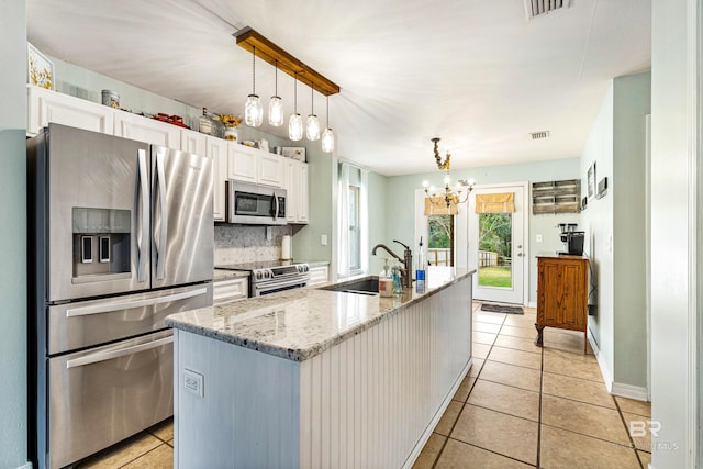 kitchen featuring pendant lighting, sink, a kitchen island with sink, stainless steel appliances, and white cabinets