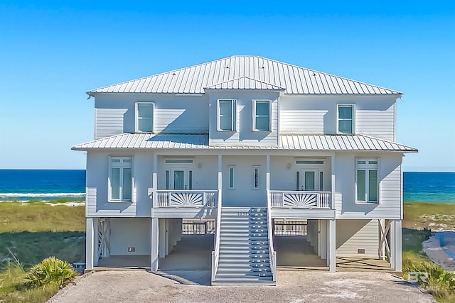 coastal home featuring a water view, a carport, a porch, and a beach view