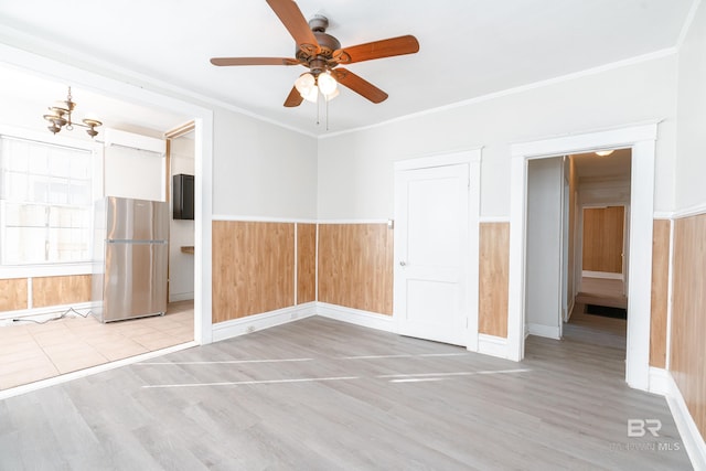 spare room with ceiling fan with notable chandelier, ornamental molding, and light wood-type flooring