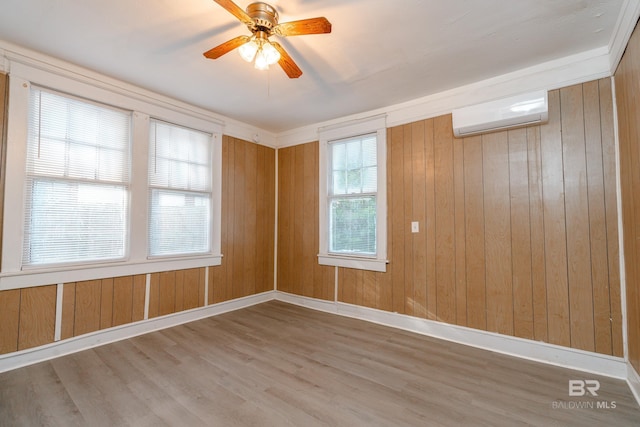 spare room with ceiling fan, hardwood / wood-style flooring, wood walls, and a wall mounted air conditioner