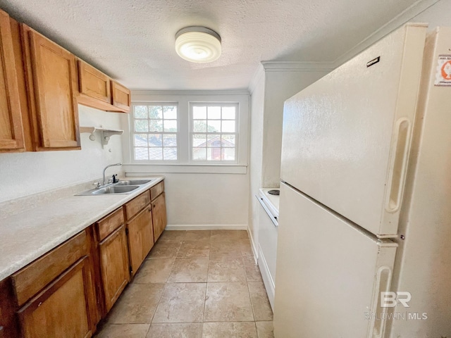 kitchen with sink, white refrigerator, ornamental molding, and a textured ceiling