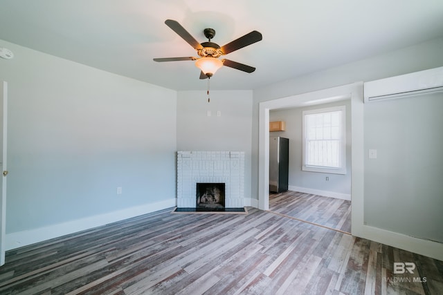 unfurnished living room featuring a wall unit AC, ceiling fan, a fireplace, and wood-type flooring