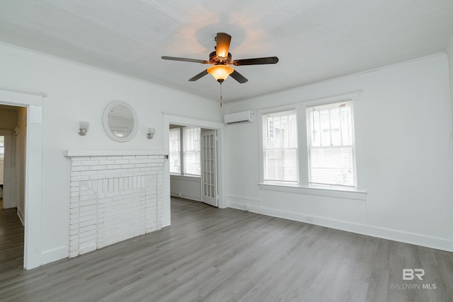 unfurnished living room featuring ceiling fan, hardwood / wood-style flooring, ornamental molding, and a wall mounted air conditioner