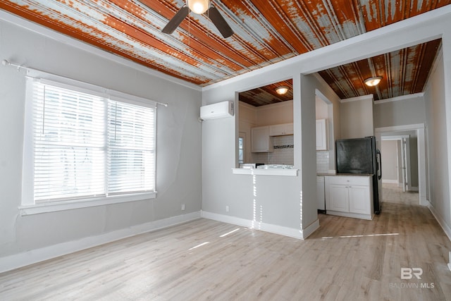 unfurnished living room with ceiling fan, a wall unit AC, light wood-type flooring, wood ceiling, and ornamental molding