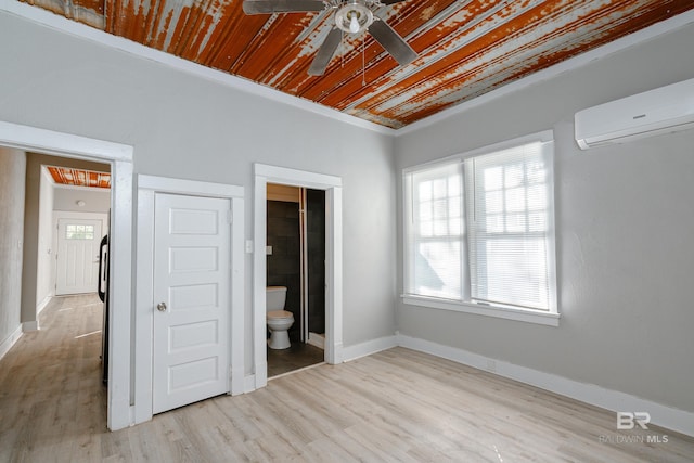 unfurnished bedroom with wood ceiling, connected bathroom, a wall mounted AC, light wood-type flooring, and ceiling fan