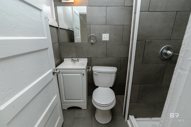 bathroom featuring tile patterned floors, vanity, tile walls, toilet, and walk in shower