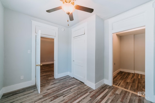 unfurnished bedroom featuring ceiling fan, a closet, and dark wood-type flooring