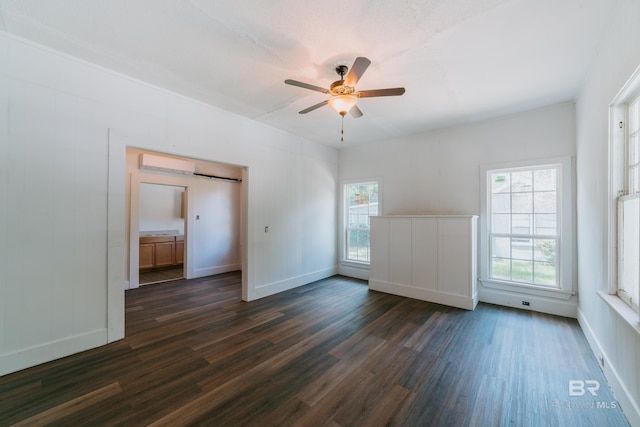 empty room featuring a textured ceiling, ceiling fan, dark hardwood / wood-style flooring, and a wall mounted AC