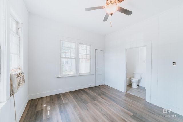 unfurnished bedroom with ceiling fan, cooling unit, ensuite bathroom, and hardwood / wood-style floors