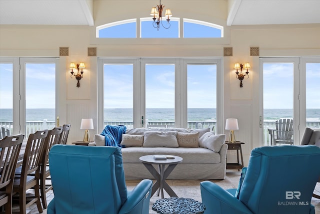 living room with a water view, a notable chandelier, and vaulted ceiling