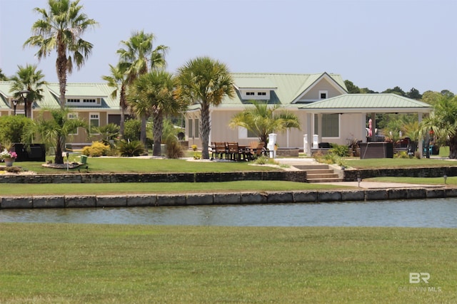 rear view of property with a water view and a lawn