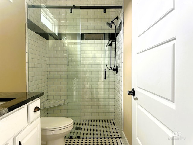 bathroom featuring tile patterned floors, vanity, a shower with shower door, and toilet