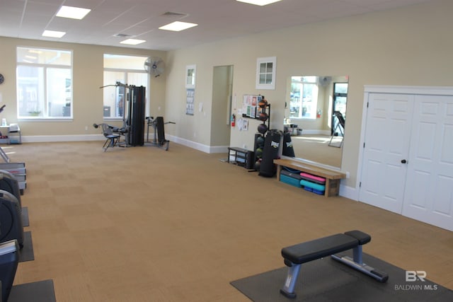 exercise room featuring light carpet, a paneled ceiling, and plenty of natural light