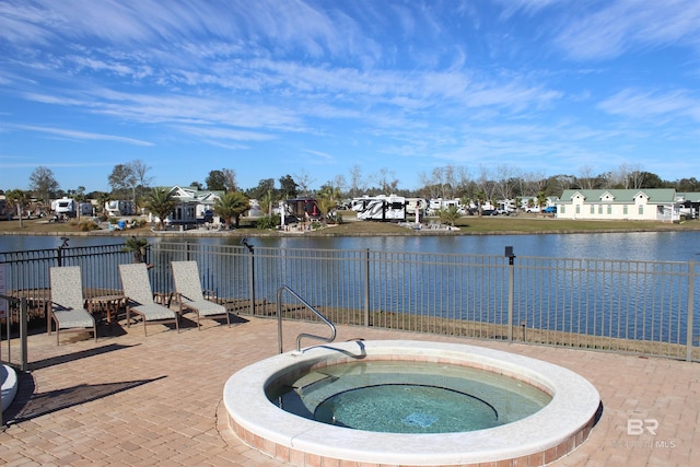 view of pool with a water view, a patio, and a hot tub