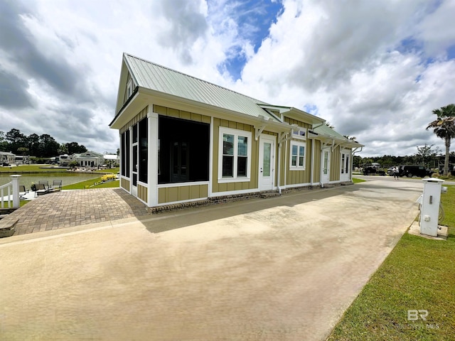 view of property exterior with a sunroom, a yard, and a water view