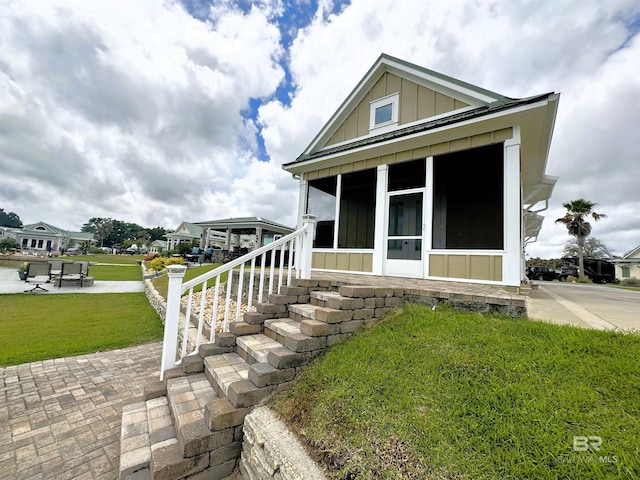 view of front of home with a sunroom and a front lawn