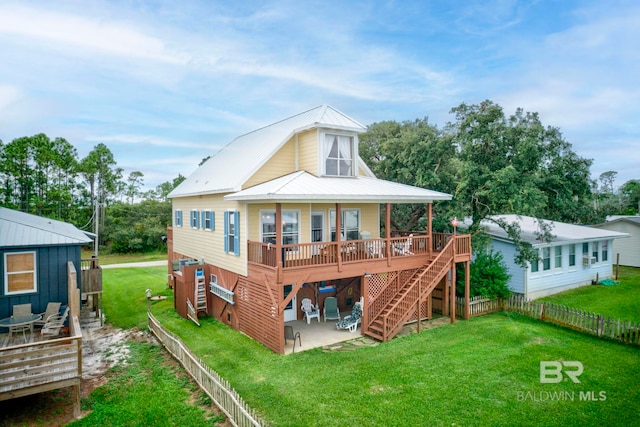 rear view of house featuring a yard, a wooden deck, and a patio area